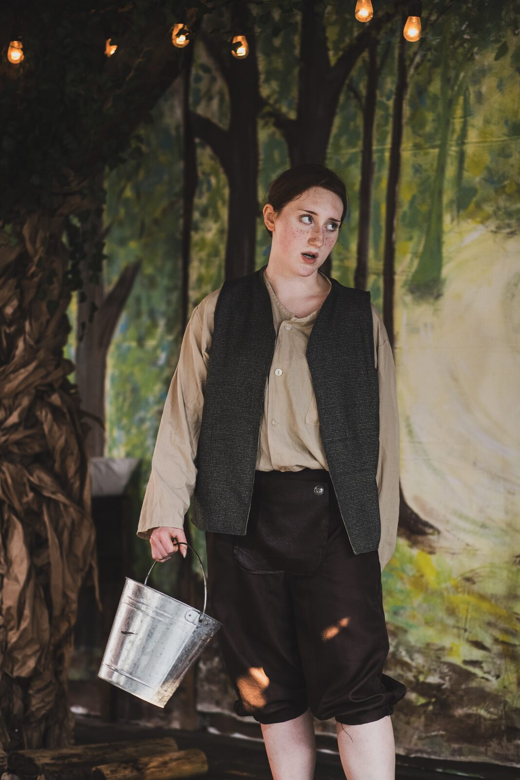Everleigh Brouse as Hansel, carrying a pail in the woods